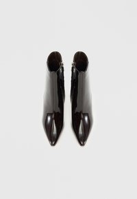 Botas de tornozelo de couro verniz preto com bicos pontudos, fecho com zip e um design elegante. Textura suave com linhas limpas e detalhe mínimo.