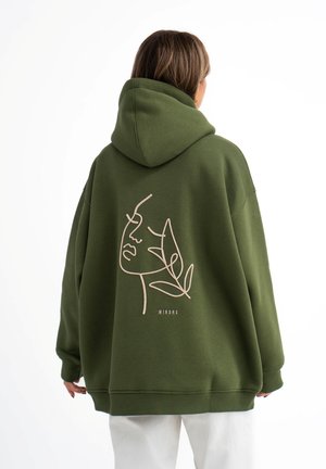 Groene oversized hoodie met een capuchon, met een minimalistische lijntekening van een gezicht en bladeren in beige op de achterkant. Gemaakt van een katoenmix.