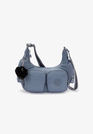 Blue crossbody bag with two front zip pockets, a black plush keychain, and adjustable striped shoulder strap against white background.