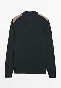 Donkergroene trui met lange mouwen, voorzien van lichtbruine schouderstukken en een geribbelde zoom. Glad textuur met een kraag aan de hals.