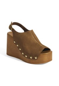 Bruine suède wedge sandaal met een open teen, slingbackband en gouden studs langs de zijkant. Houten platformbasis voegt hoogte toe.
