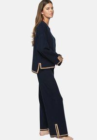 Ensemble de détente bleu marine en tissu doux ; dispose de manches larges et d'un bord beige contrastant aux poignets et à l'ourlet ; coupe décontractée avec un pantalon droit.