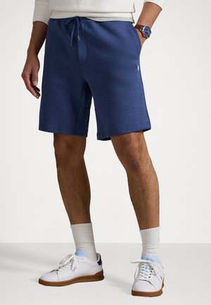 Navy blue cotton blend shorts with an elastic waistband, side pockets, and a small logo. Worn with white sneakers and banded socks.