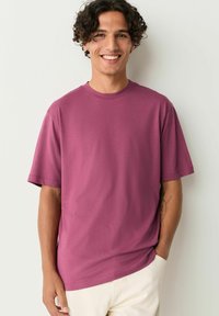 Kortærmet T-shirt med rund hals i dyb mauve, fremstillet af blød bomuldsblanding, med afslappet pasform og minimal syning.