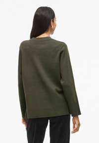 Maglione verde a maglia con scollatura rotonda, maniche lunghe e una vestibilità leggermente oversize. Presenta polsini a coste e un orlo dritto.