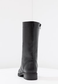 Bota de cuero negra hasta la rodilla con textura suave, puntera redondeada y un tacón bajo en bloque. Presenta una cremallera lateral y costuras limpias.