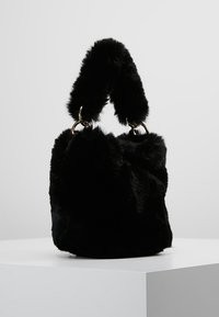 Czarna torebka z futerka syntetycznego o miękkiej fakturze, zaokrąglonym kształcie i podwójnych uchwytach w formie pętli, ozdobiona złotymi elementami metalowymi.