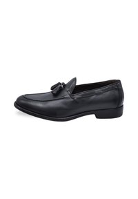 Black leather loafers with tassel detail, featuring a stitched design and flat sole. Smooth texture with a classic shape.