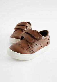 Baskets en cuir marron avec deux sangles Velcro ajustables, des détails perforés et une semelle en caoutchouc blanche. Design à bout rond.