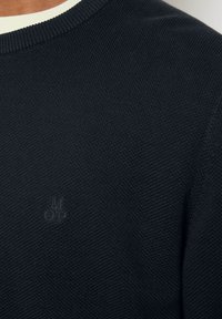 Dunkelblauer gestrickter Pullover mit Rundhalsausschnitt, strukturiertem Stoff und einem dezenten gestickten Logo auf der Brust.