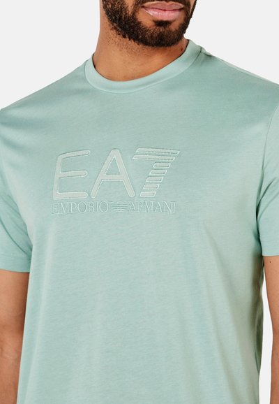 Camiseta de manga corta verde claro con el logo bordado de EA7 Emporio Armani en hilo de contraste. Tejido suave con una textura lisa.