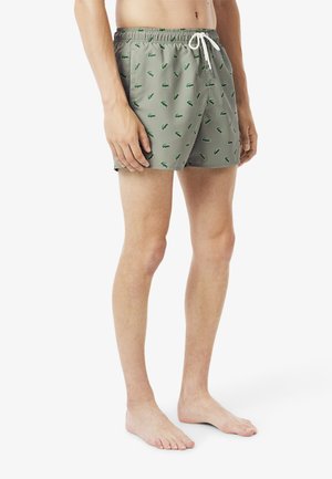 Shorts de bain verts avec un petit motif contrastant, taille élastique, fermeture à cordon de serrage et coupe décontractée.