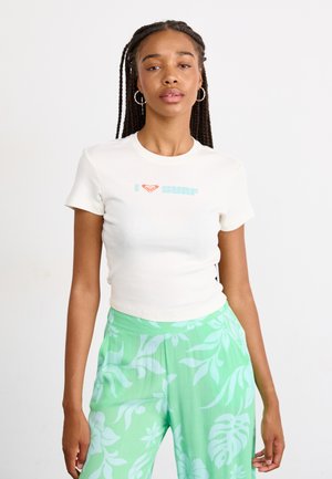 Kremfarget T-skjorte med kort erme og lys blå tekst "I ❤️ surf" samt en rød hjerte-logo. Kombinert med grønne bukser med blomsterprint og vidde.