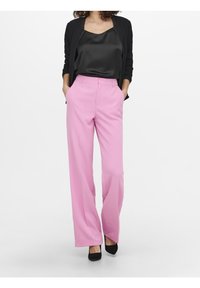 Rooze wijde broek met een gladde textuur, gecombineerd met een zwarte satijnen top en een zwarte jas. G gedragen met zwarte hakken.