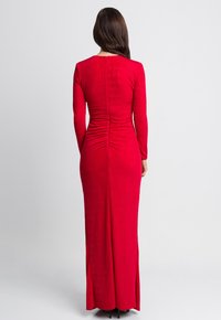 Czerwona sukienka z długimi rękawami o dopasowanym kroju, zebrana tekstura z tyłu i rozcięciem na dole, wykonana z miękkiego, gładkiego materiału.