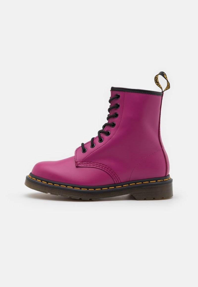 Botte en cuir violet à lacets avec semelle noire, coutures jaunes et languette de tirage marquée sur fond blanc.