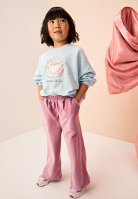 Svetlo modra majica z motivom vroče čokolade; rožnate hlače iz korduroja; kombinirano s sivoroznmi supergami; teksturirana tkanina in pastelne barve.