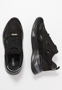 Sneaker in suede nero e mesh con suole spesse a motivo, lacci neri, charm brand dorato e logo "Liu Jo" all'interno della zona del tallone.