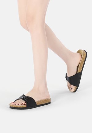 Schwarze Rutschen-Sandalen mit einem breiten Riemen und dekorativer Schnalle, Korkfußbett, strukturiertem Sohle und offenem Zehendesign. Lässiges Schuhwerk für warmes Wetter.