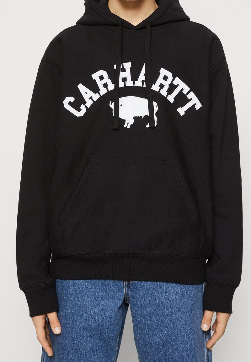 Černá mikina s kapucí s bílým nápisem „CARHARTT“ a grafikou bizona. Má přední kapsu a nastavitelné šňůrky na kapuci.