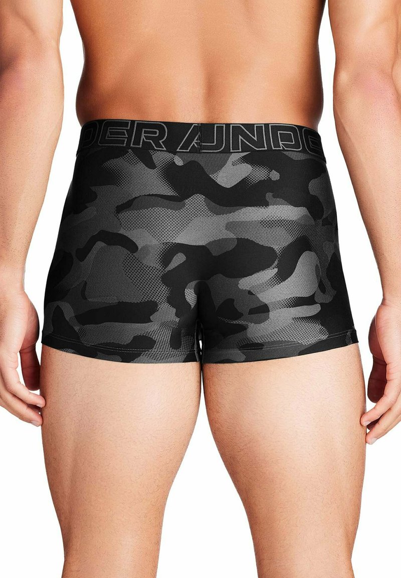 Black camo-patterned men's underwear with a textured waistband labeled "Under Armour." Features a snug fit and short leg design.