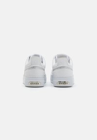 Sneaker bianchi in pelle con finitura testurizzata, caratterizzate da un accento argentato e un marchio sul tallone. Suola in gomma spessa per stabilità.