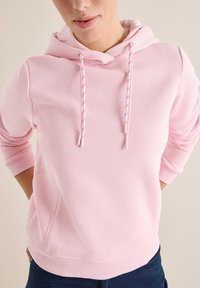 Felpa con cappuccio rosa, dal morbido tessuto, con lacci con punte metalliche, polsini a costine e una vestibilità rilassata.