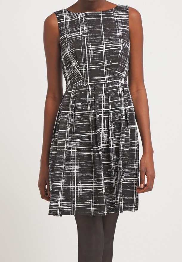 Sort kjole med ærmeløst design, der har et hvidt linjemønster. Udsvinget nederdel og tætsiddende liv skaber en defineret silhuet.