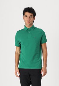 Grøn bomulds polo t-shirt med krave og to knapper, med et lille logo på venstre bryst. Korte ærmer og en lige kantdesign.