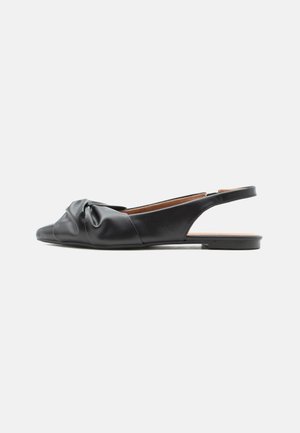 Μαύρο δερμάτινο επίπεδο παπούτσι slingback με περίτεχνο κόμπο πάνω από τα δάχτυλα και χαμηλό τακούνι, εμφανίζεται σε προφίλ με κατεύθυνση προς τα αριστερά.