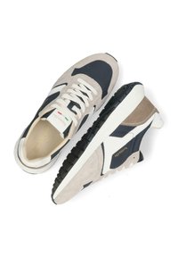 Baskets en daim beige et marine, avec une semelle en caoutchouc blanc. Présente un design à lacets et un logo doré sur le côté.