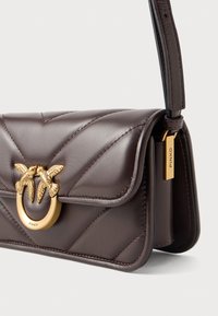 Bolsa transversal em couro castanho escuro, acolchoada, com fecho dourado, apresentando duas aves e uma etiqueta dourada gravada com "PINKO" na alça.