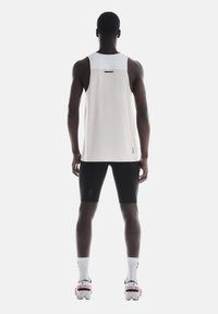 Hvid ærmeløs atletisk tanktop med tekstureret stof, sorte shorts og multicolore løbesko; enkelt design med en sporty pasform.