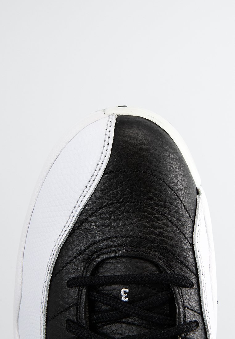Czarno-białe trampki z teksturowaną czarną skórzaną cholewką i gładkimi białymi bocznymi elementami, z czarnymi sznurowadłami i kontrastującą białą podeszwą.