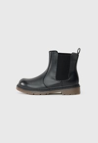 Bottines Chelsea noires en cuir lisse, avec des panneaux latéraux en élastique et une semelle en caoutchouc marron. Dotées d'une languette à l'arrière pour un enfilage facile.