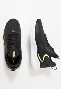 Černé sportovní boty s síťovaným svrškem, zdobené růžovými a neonově žlutými akcenty. Zakulacená bílá podrážka s texturovanými detaily, ploché tkaničky.