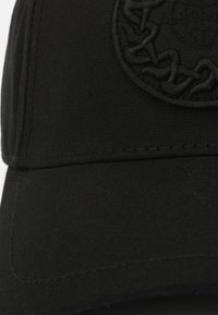 Cappellino da baseball nero realizzato in tessuto testurizzato, caratterizzato da un design ricamato circolare con un motivo intrecciato sul fronte.