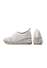 Bílé síťované boty na slip-on s vzorovanými detaily, vyvýšená hnědá podešev s designem listu a poutko v zadní části pro snadné nazouvání.