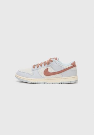 Lavtop sneaker i hvid og lysegrå mesh med støvet rosa Nike swoosh og snørebånd, på en beige sål, vist fra siden på hvid baggrund.