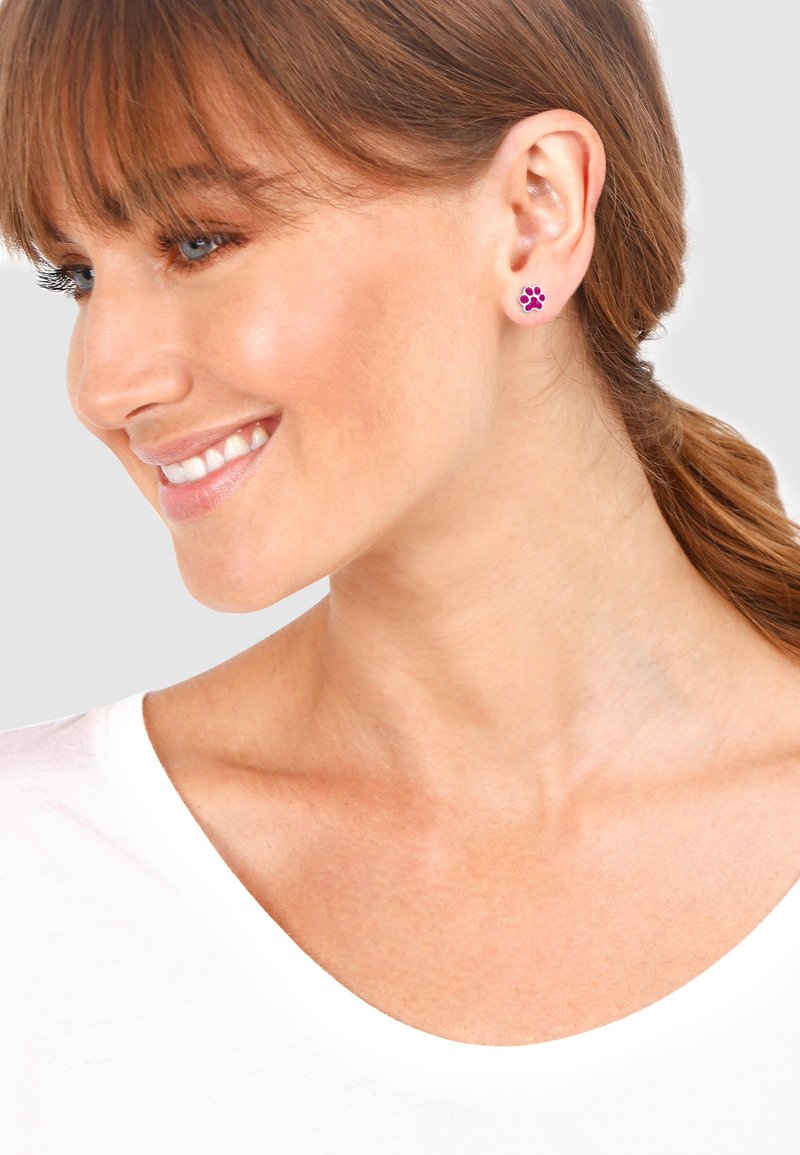 Clous d'oreilles en émail violet en forme d'empreinte de patte, avec une finition brillante, montés en métal ton argenté. Design petit et rond, adapté à un usage quotidien.