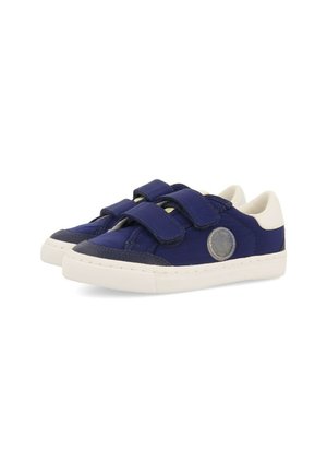 Zapatillas de lona azules con acentos blancos y correas de Velcro. Incluye un logotipo circular en el lateral y una suela de goma texturizada.
