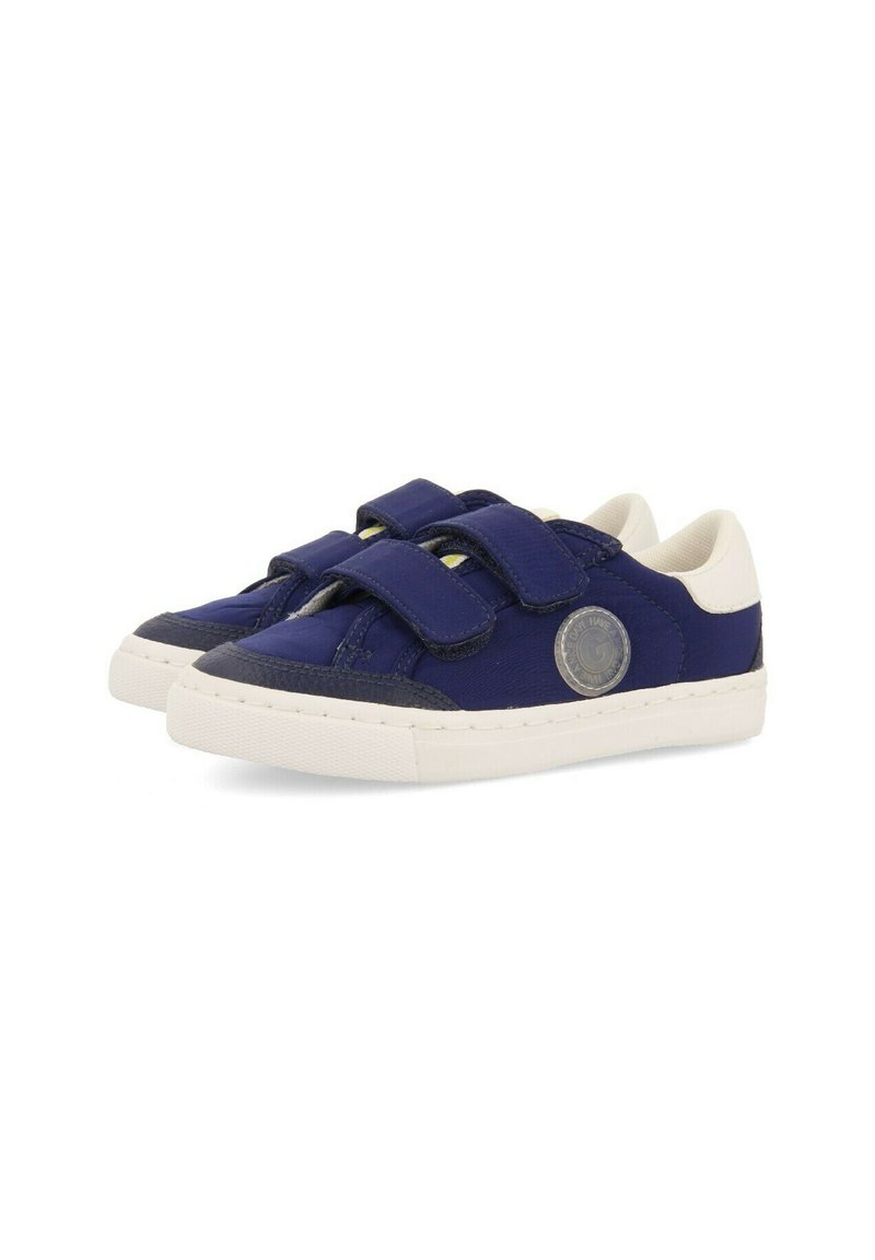 Zapatillas de lona azules con acentos blancos y correas de Velcro. Incluye un logotipo circular en el lateral y una suela de goma texturizada.