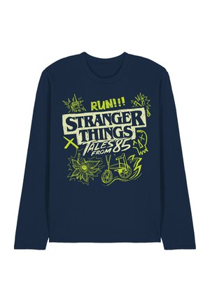 Navy blue long-sleeve shirt with neon green "Stranger Things Tales from 85" text, a bike, radio, flower, skull, and lightning bolt graphics.