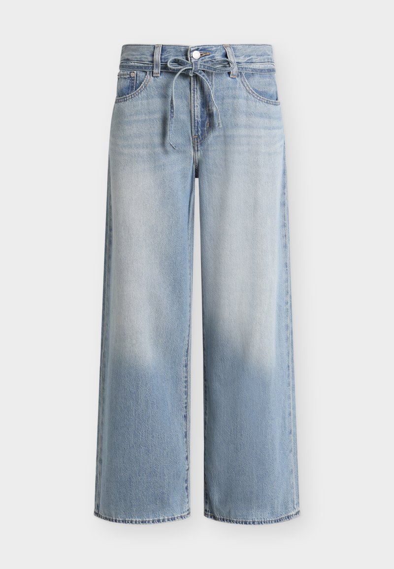 Φαρδιά τζιν σε ανοιχτό γαλάζιο με ξεβάμματα στους μηρούς, μπροστινό κούμπωμα με κουμπιά και φερμουάρ, θηλιές για ζώνη και δεμένη κορδονέ ζώνη στη μέση.