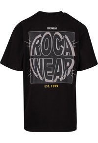 Juodas medvilninis marškinėliai su dideliu, ryškiu "ROCA WEAR" grafiku pilka ir geltona spalvomis. Turi apvalią iškirptę ir trumpas rankoves. Įsteigta 1999 metais.