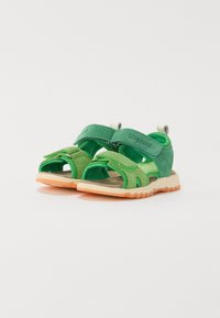 Green children's sandals made of suede and fabric, featuring adjustable straps, open toe design, and textured orange rubber soles.