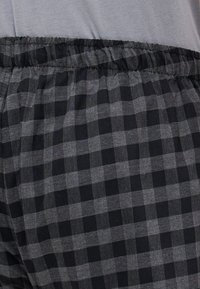 Shorts de détente à carreaux noirs et gris avec une taille élastique, offrant une texture douce et un design ample.