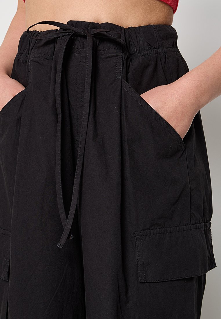 Pantaloni cargo neri con vita elastica, chiusura con cordino e ampie tasche laterali, realizzati in tessuto leggero.