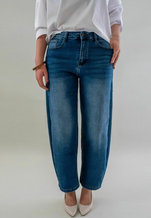 Lichtblauwe high-waisted jeans met een relaxed fit, voorzien van vijf zakken, riemlussen en vervaagde details. Gecombineerd met nude hakken.