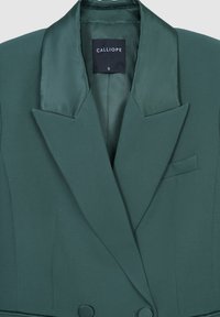 Blazer su misura verde scuro con rever in raso, chiusura a due bottoni, taschino sul petto e etichetta "CALLIOPE" di taglia piccola all'interno del colletto.